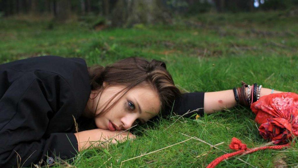 Dreileben: A woman lies on the grass in Christian Petzold's Beats Being Dead film.