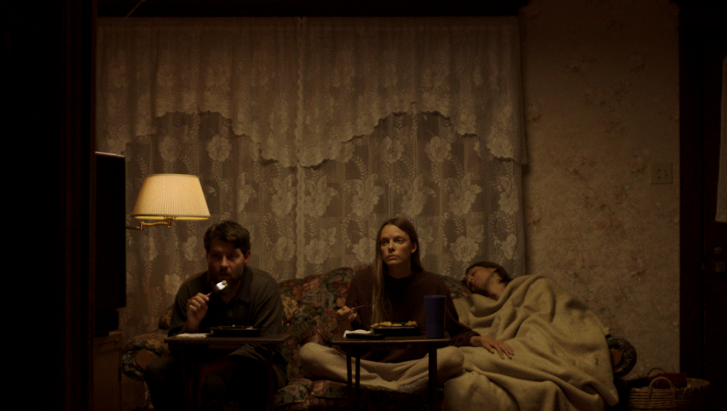 My Heart Can’t Beat Unless You Tell It To | Jonathan Cuartas My Heart Won't Beat Unless You Tell It To movie scene. Three people on a couch, one sleeping. Dark, moody lighting.