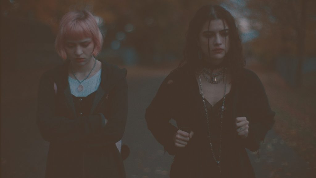 We Need to Do Something | Sean King O’Grady We Need to Do Something film still. Two young women, one with pink hair, stand outside. Dark aesthetic.