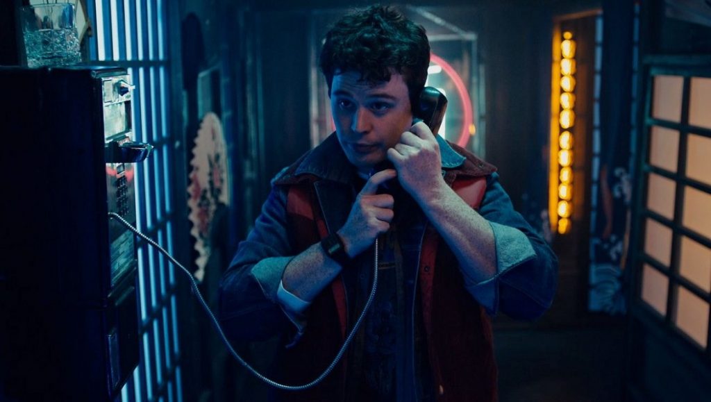 Vicious Fun | Cody Calahan Evan Marsh in Vicious Fun movie still. Man using a payphone in a neon-lit setting. Cody Calahan film scene.