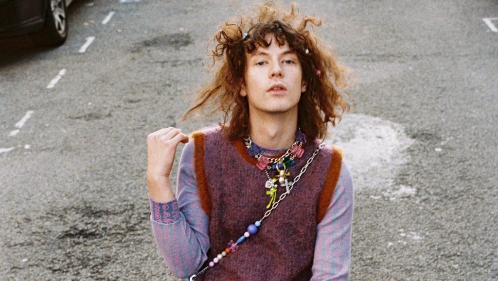 Best Albums of 2021: Bladee | The Fool Bladee, May 2021 album roundup. Swedish rapper with brown hair, wearing a sweater vest and colorful beaded necklace.