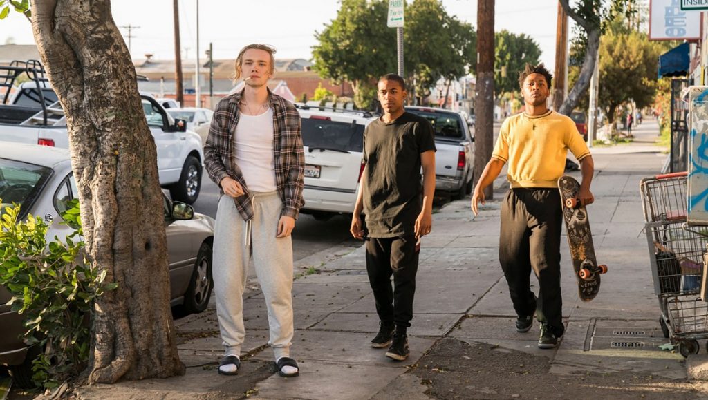 Gully film still: Three young men walking on a city sidewalk. One carries a skateboard. Nabil Elderkin film.