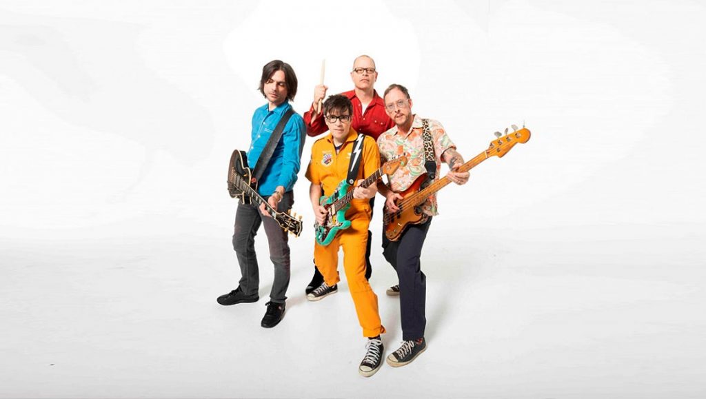 Weezer | Van Weezer Weezer band portrait. Rivers Cuomo with guitar, Brian Bell, Patrick Wilson with drumsticks, and Scott Shriner.