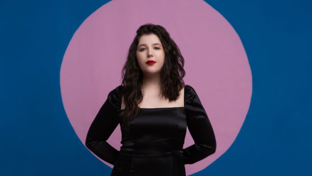 Lucy Dacus | Home Video Lucy Dacus portrait. Singer in a black dress with pink and blue background. Matador Records artist.