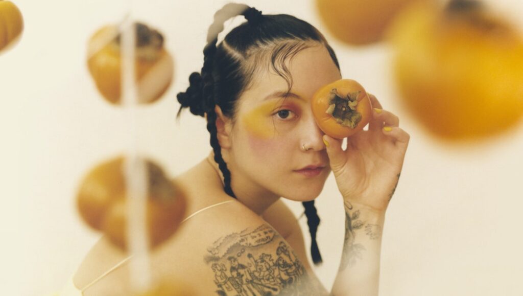 Japanese Breakfast | Jubilee Japanese Breakfast, Michelle Zauner. One of the top albums of 2021. Woman holding persimmon.