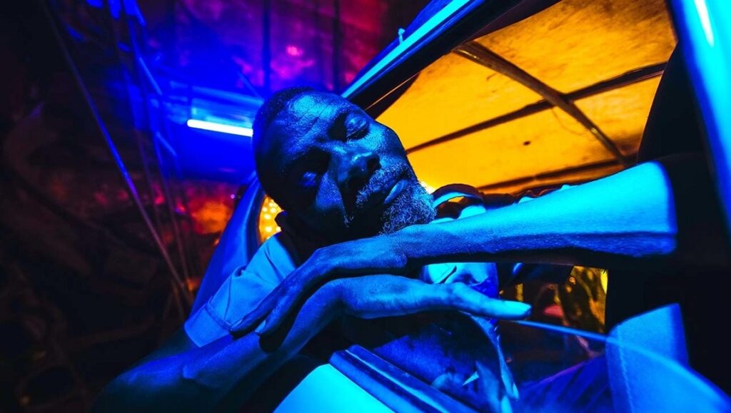 Air Conditioner | Fradique Fradique's Air Conditioner film still. Man rests, bathed in blue and yellow light.