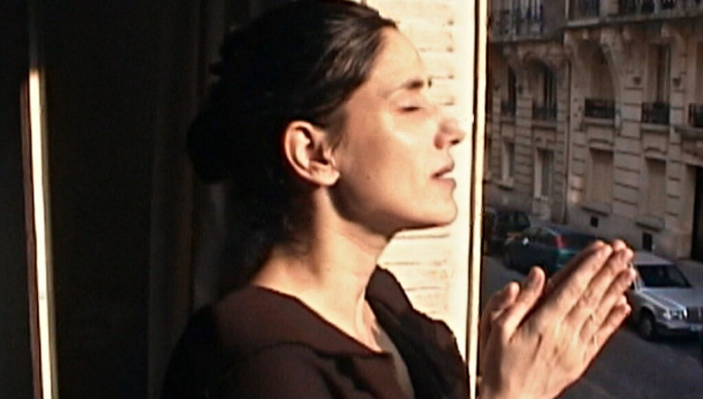 Black Notebooks | Shlomi Elkabetz Woman with hands together looking out window in Paris, France.