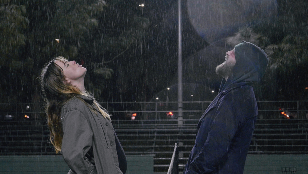 Fully Realized Humans | Joshua Leonard Fully Realized Humans film image: A man and woman look up in the rain at night.