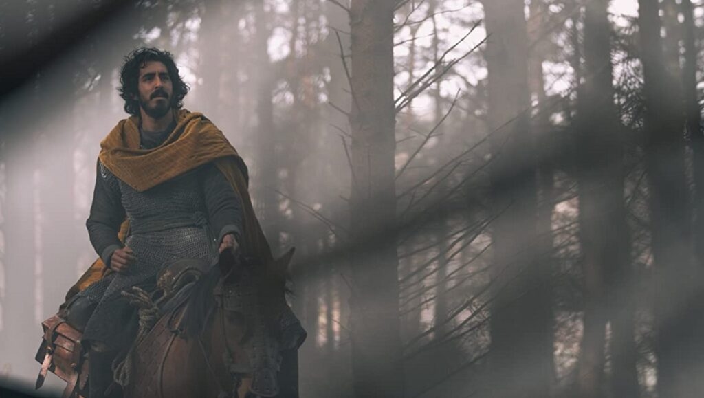 The Green Knight | David Lowery Dev Patel as Sir Gawaine in The Green Knight movie. Knight on horseback in a misty forest.