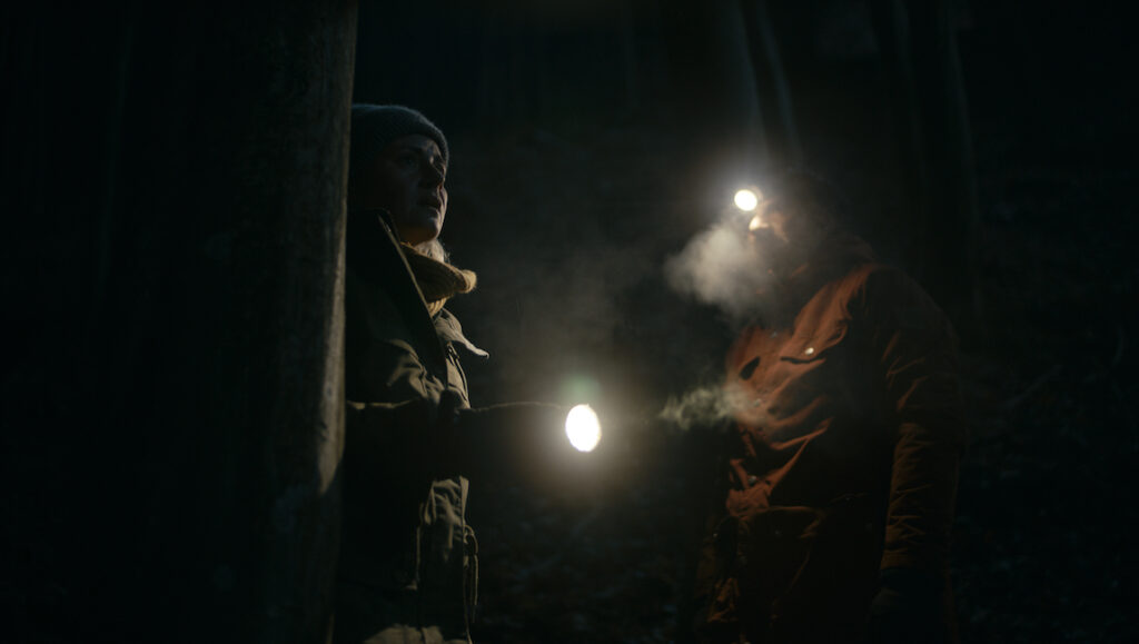 Intregalde film still from Cannes Film Festival 2021. Two people with headlamps in a dark, outdoor setting.