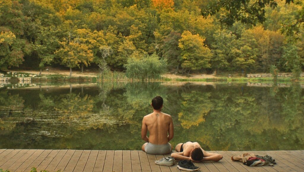 The Man with the Answers | Stelios Kammitsis Man meditates by lake on dock. Autumn trees reflected in water. Wellness and relaxation concept.