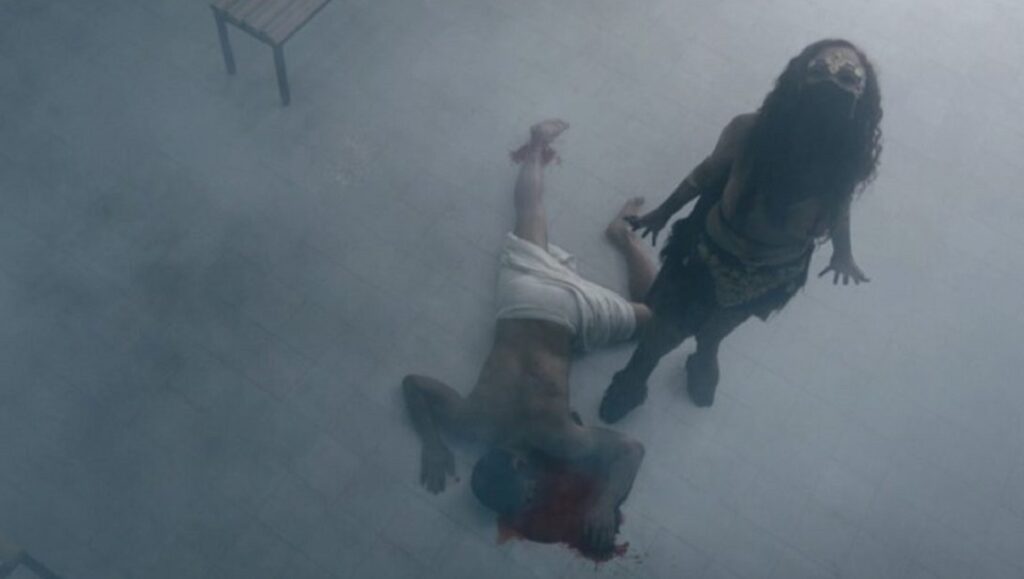 Kandisha movie scene. Woman standing over a prone, bloodied man. Horror film.