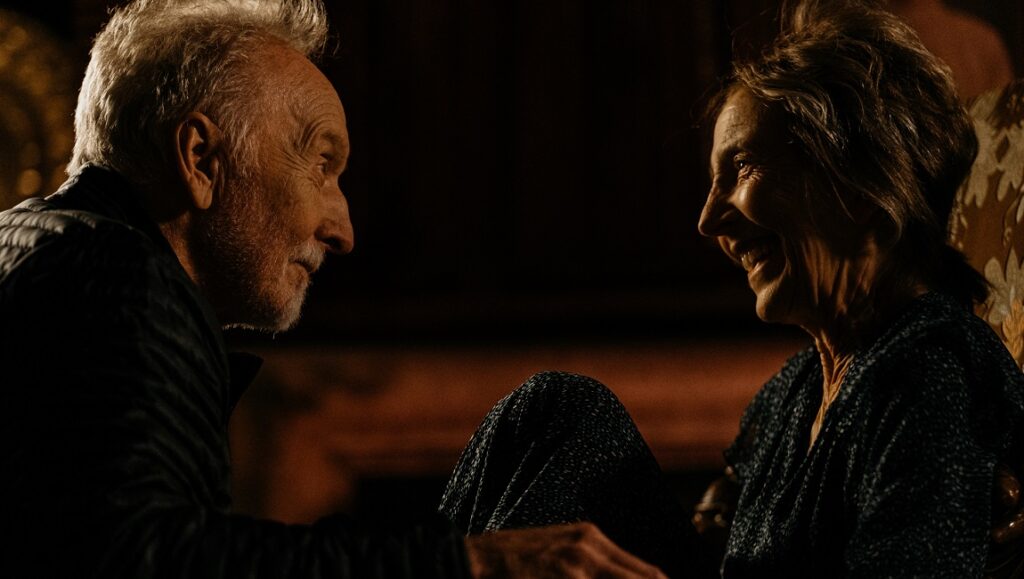 The Call | Timothy Woodward Jr. The Call movie scene: Lin Shaye and Tobin Bell face each other, smiling in a dimly lit room.