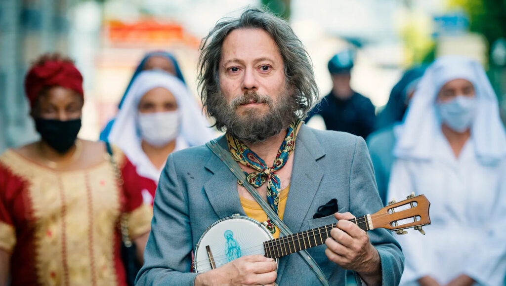 Tralala | Arnaud Larrieu & Jean-Marie Larrieu Man with banjo, Tralala movie scene. People in masks, nuns. Musical film.