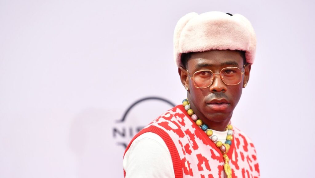 Album Roundup — June 2021 | Part 4: Tyler, the Creator, Amythyst Kiah, The Mountain Goats Tyler, the Creator, wearing a fur hat, glasses, and a colorful necklace. Stylish rapper.