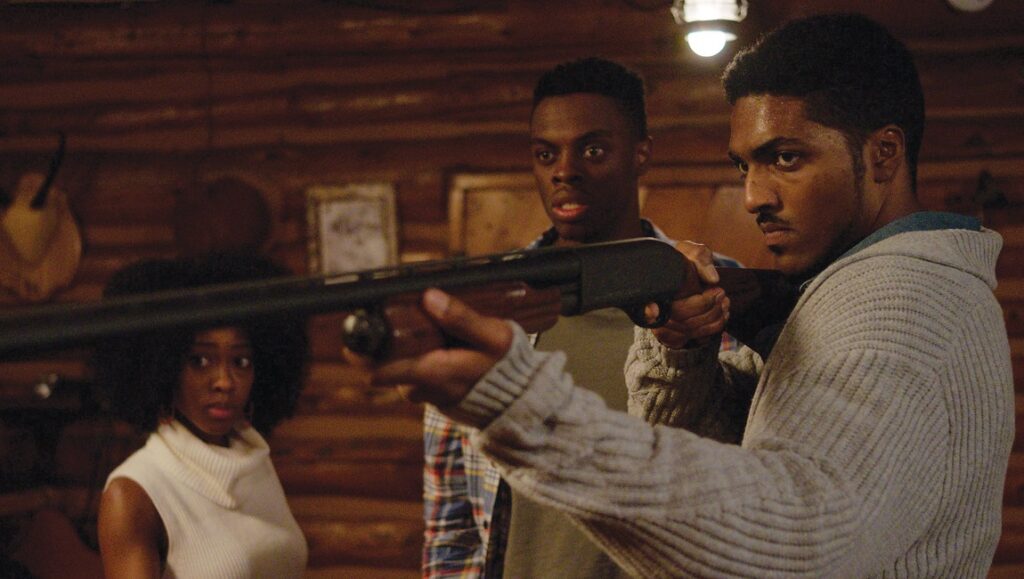 Blood Conscious | Timothy Covell Blood Conscious movie still. Three people in a cabin. Man aims a shotgun looking serious.