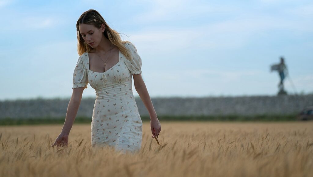 Flag Day | Sean Penn Still from Flag Day: Woman in a floral dress walking through a wheat field.