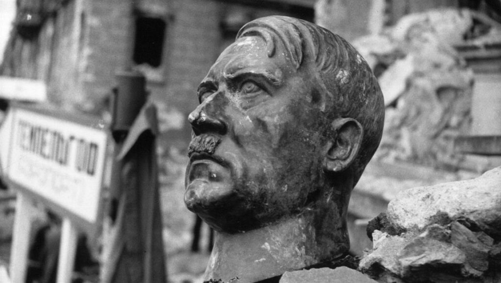 The Meaning of Hitler | Michael Tucker & Petra Epperlein Black and white image of a broken Hitler statue in rubble. The Meaning of Hitler documentary.