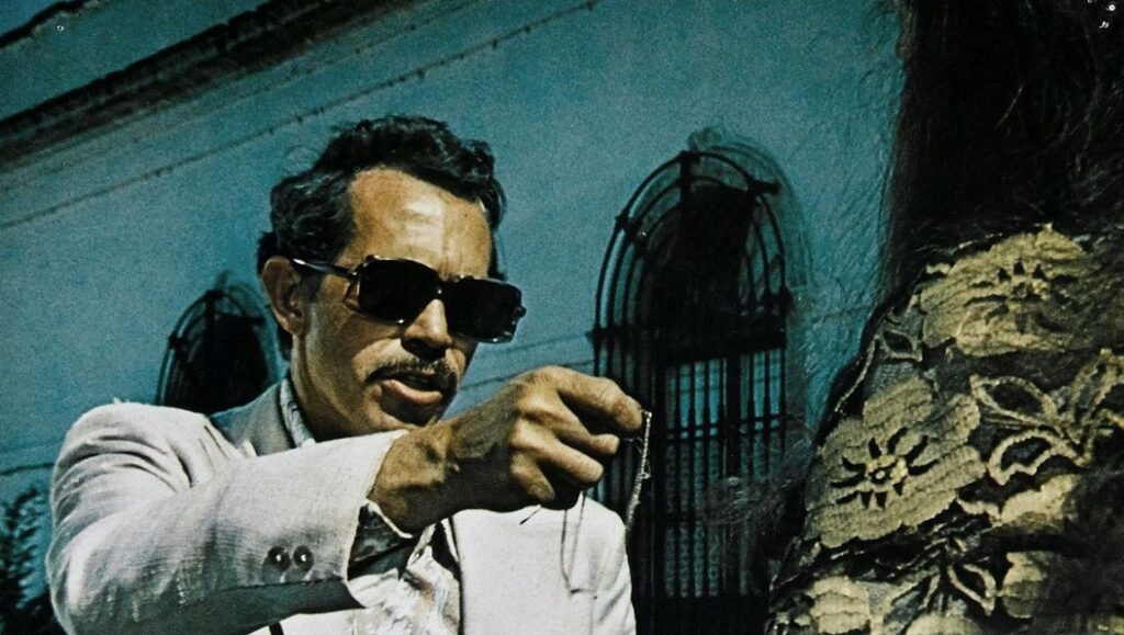 Still from Bring Me the Head of Alfredo Garcia, a Sam Peckinpah film. Man with sunglasses holding a necklace.
