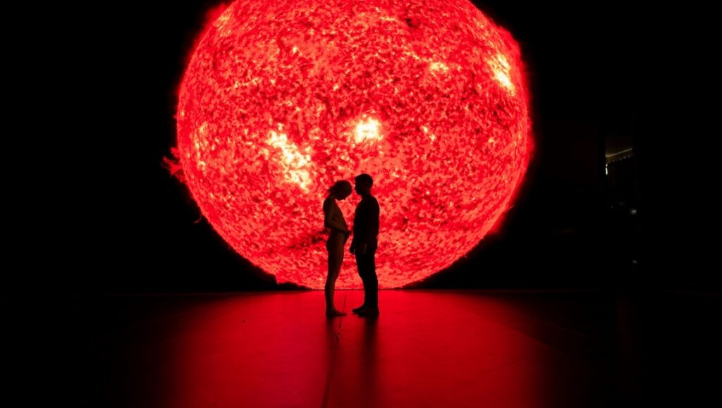 Ema movie still: Silhouette of couple against a red sun. Pablo Larrain film.