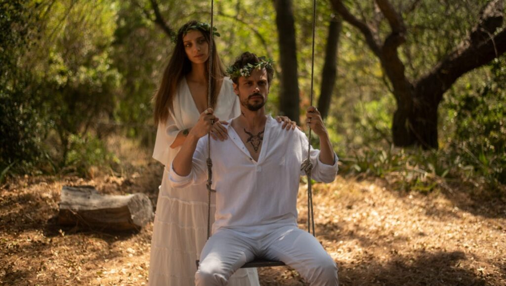 King Knight movie still. Man on a swing with a woman behind him, both wearing white robes and wreaths. Fantasia Fest 2021.