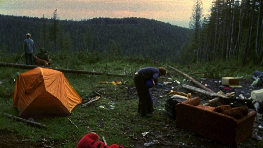 Old Joy movie scene. Camping in the forest with a tent, sofa, and people. William Friedkin film.