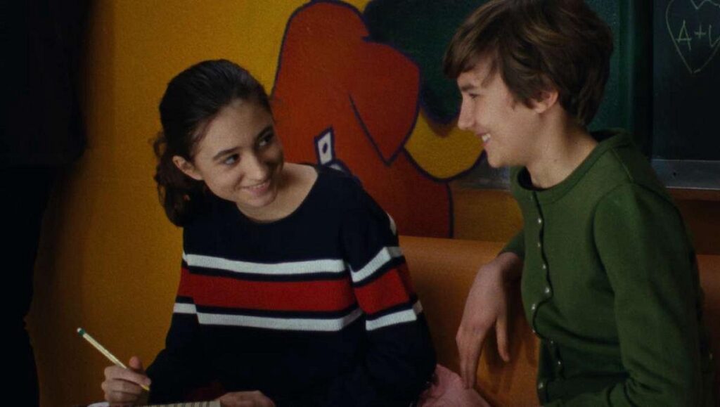Petite Solange | Axelle Ropert Petite Solange film still. Two young people smile at each other in a classroom.