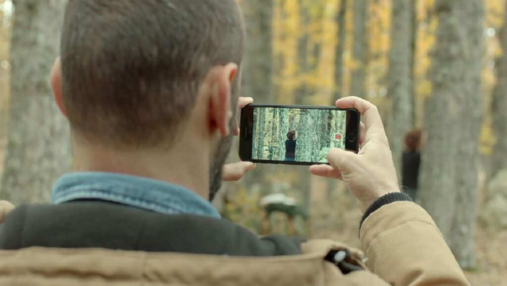 The River | Ghassan Salhab The River film still: Man records person in forest with phone. Ghassan Salhab movie scene.
