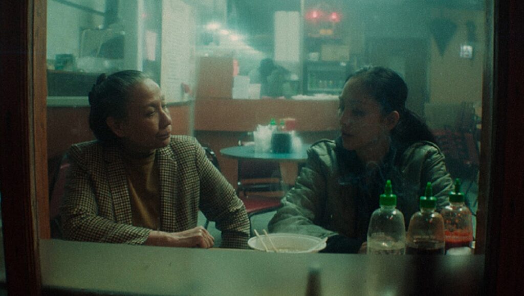 Two women in a diner, seen through a window, in Snakehead by Evan Jackson Leong.