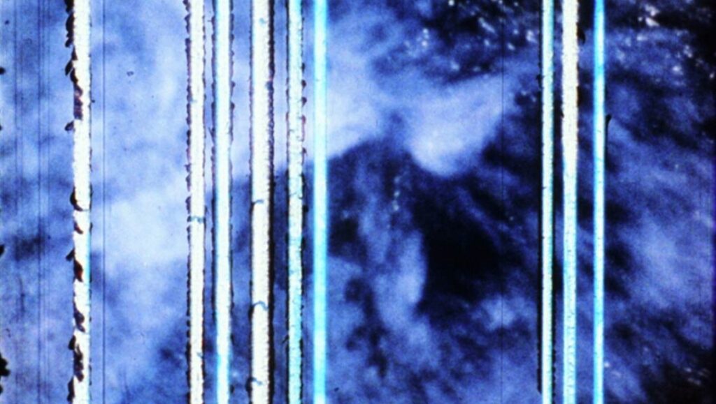 Abstract film still from S:TREAM:S:S:ECTION: S:ECTION:S:S:ECTIONED by Paul Sharits. Blue, white, and black. Vertical lines.