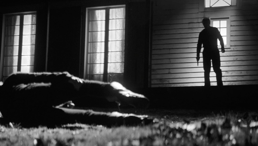 Black and white horror scene. Man with knife stands over body outside a house. Suspense, thriller.