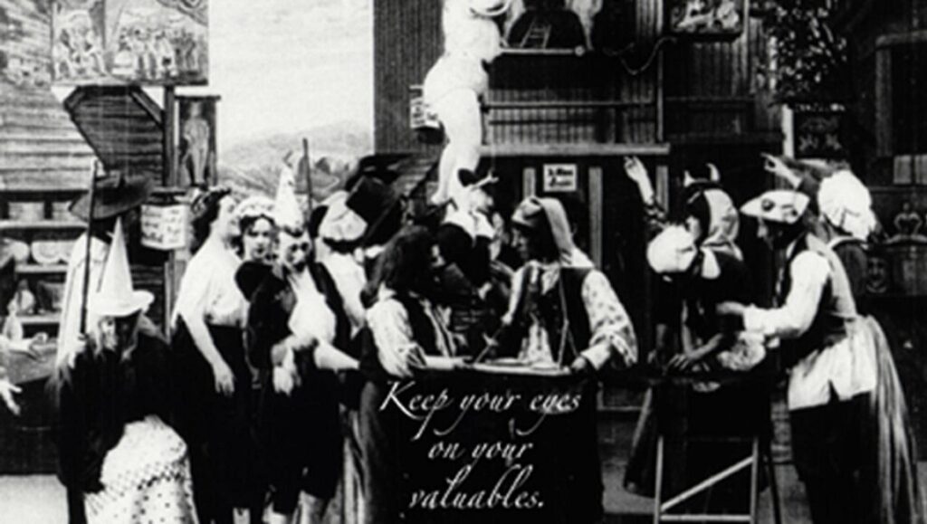 Tom, Tom, the Piper's Son film still. Silent era scene with a crowd, sign reads Keep your eyes on your valuables.