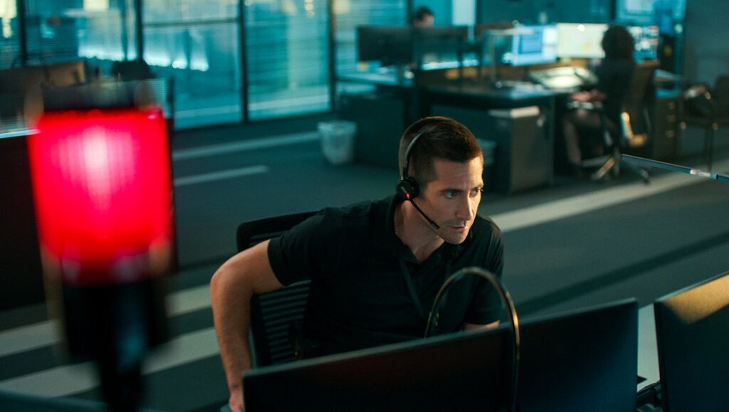 Jake Gyllenhaal in The Guilty at TIFF 2021. Actor with headset in tense 911 call center scene. Red emergency light.