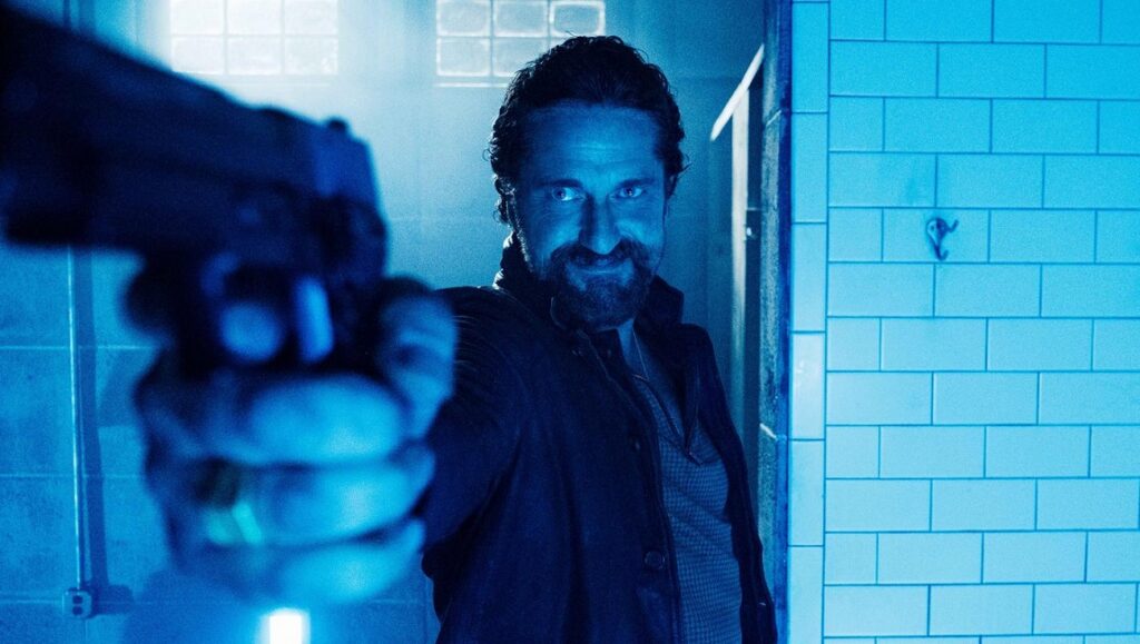 Copshop | Joe Carnahan Gerard Butler in Copshop points a gun. Joe Carnahan directs this action thriller. Cop versus hitman.