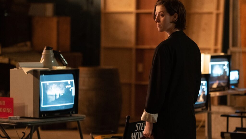 The Souvenir: Part II | Joanna Hogg Still from The Souvenir: Part II at NYFF 2021. Woman in black coat stands near vintage TV monitors and a director's chair.