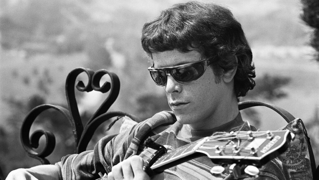 Lou Reed of The Velvet Underground plays guitar in a black and white publicity shot for NYFF 2021 documentary.