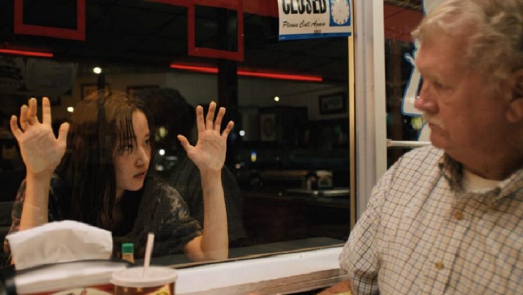 Venice International Film Festival 2021 — Dispatch 1: Mona Lisa and the Blood Moon, The Accusation, Il Buco Mona Lisa and the Blood Moon film still, Venice Film Festival 2021. Woman with hands on glass, man looks on.