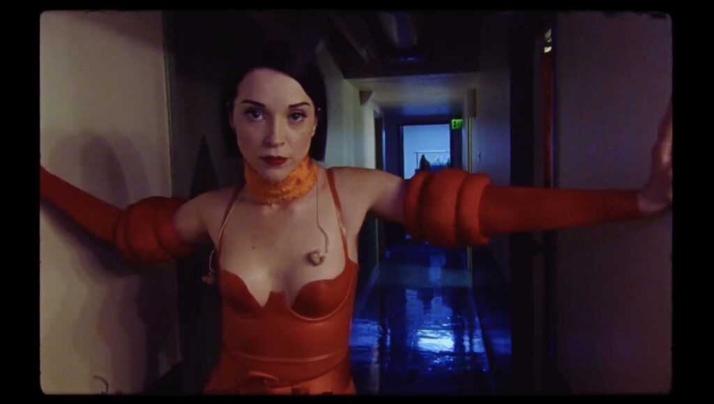 The Nowhere Inn | Bill Benz St. Vincent in The Nowhere Inn, directed by Bill Benz. Musician in red outfit stands in a hallway.