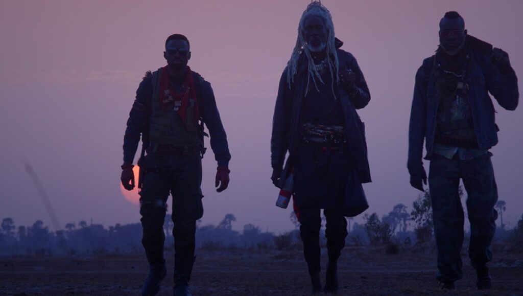 Saloum | Jean Luc Herbulot Saloum film still from TIFF 2021: Three figures walk silhouetted against a sunset.