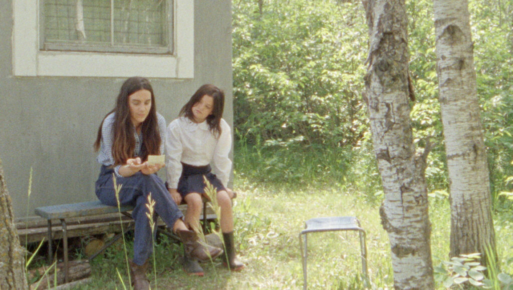 Ste. Anne film still: Two women sit outside. TIFF 2021 movie review.
