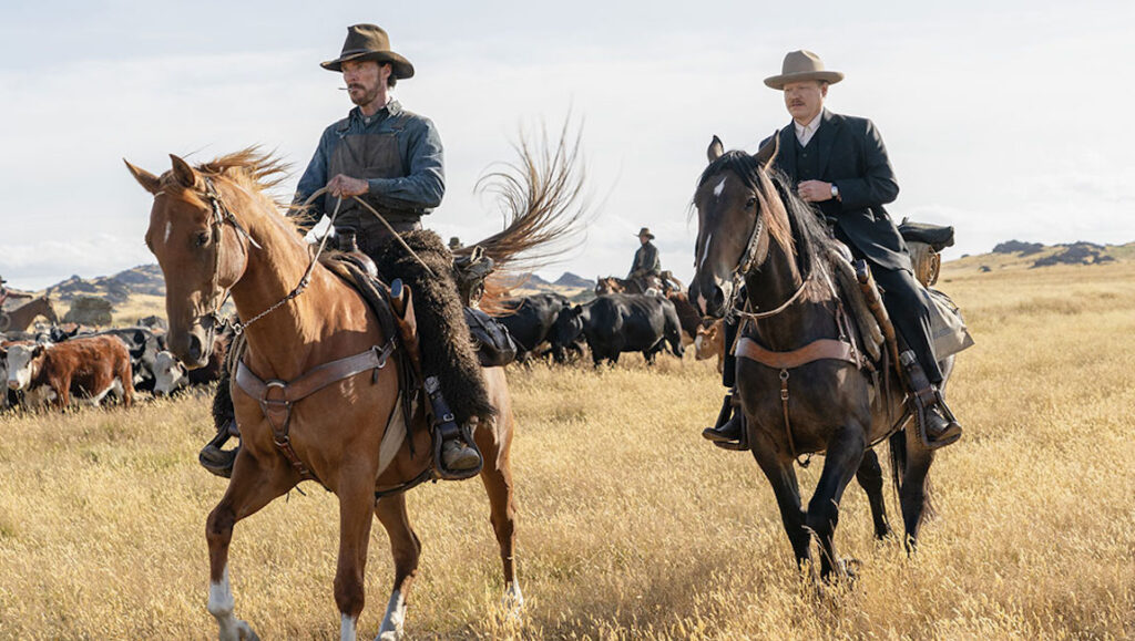 The Power of the Dog film still: Benedict Cumberbatch and Jesse Plemons on horseback herding cattle.
