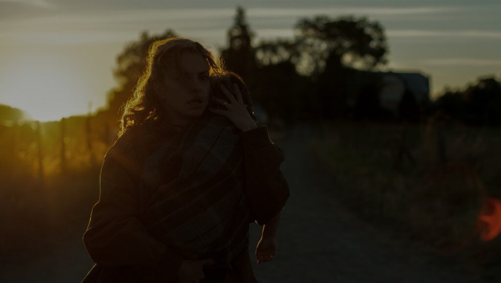 Fever Dream | Claudia Llosa Fever Dream movie scene: Woman carrying child on rural road at sunset. Claudia Llosa film.