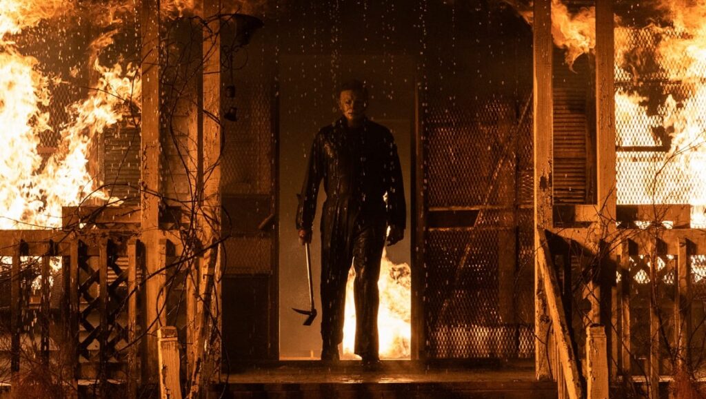 Michael Myers in Halloween Kills emerges from a burning house. Horror movie scene.