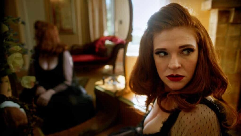 Val | Aaron Fradkin Freeland film still. Woman with red hair and red lipstick. Before We Vanish, October 2021: Freeland, Warning, Minyan.