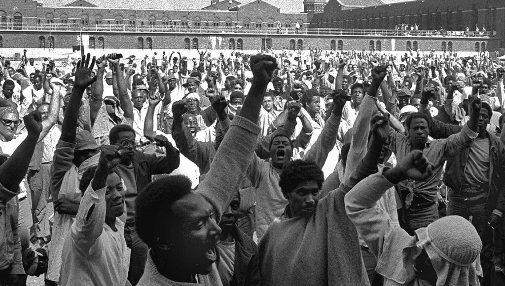 Attica | Stanley Nelson Black and white photo of the Attica Prison riot. Inmates raise fists in protest. Stanley Nelson's Attica documentary.