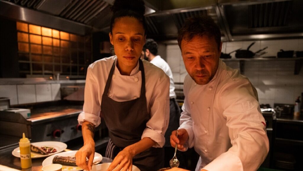 Boiling Point movie still. Chefs in a busy restaurant kitchen plating food.