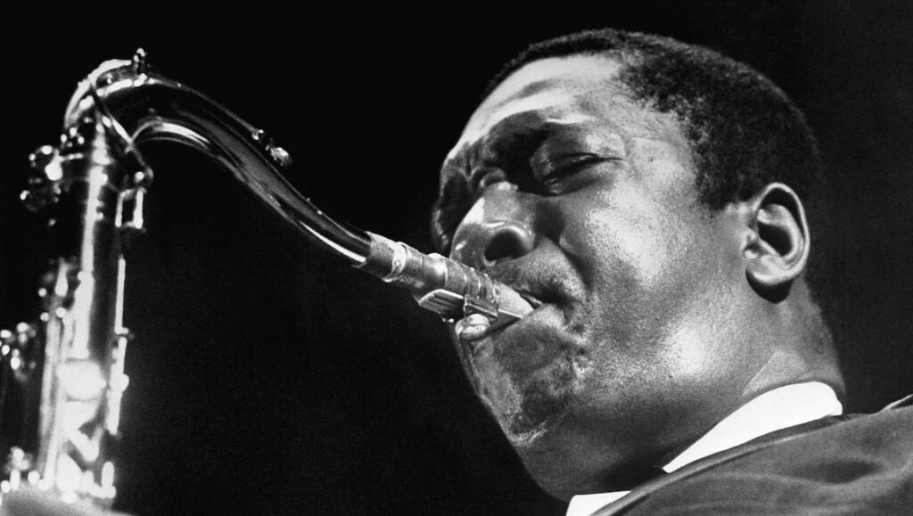 John Coltrane plays the saxophone in a black and white close-up. Jazz music legend.
