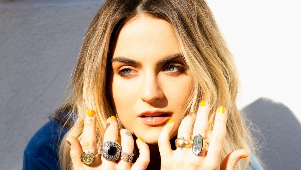 JoJo | Trying Not to Think About It JoJo poses with statement rings and yellow nails. Blonde hair, blue eyes. Singer JoJo.