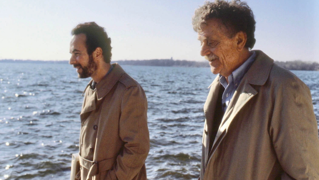 Kurt Vonnegut: Unstuck in Time documentary film still. Two men in trench coats by the water. DOC NYC 2021 film festival.