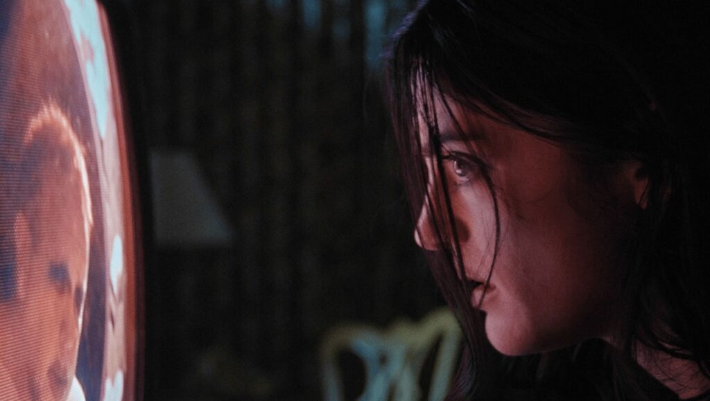 Night at the Eagle Inn movie scene: Woman watching TV with a concerned expression. Horror film.